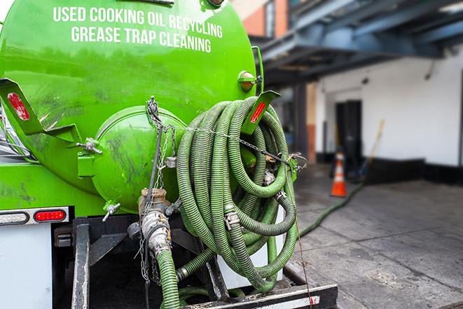 a technician pumping a grease trap in a commercial building in Dupo